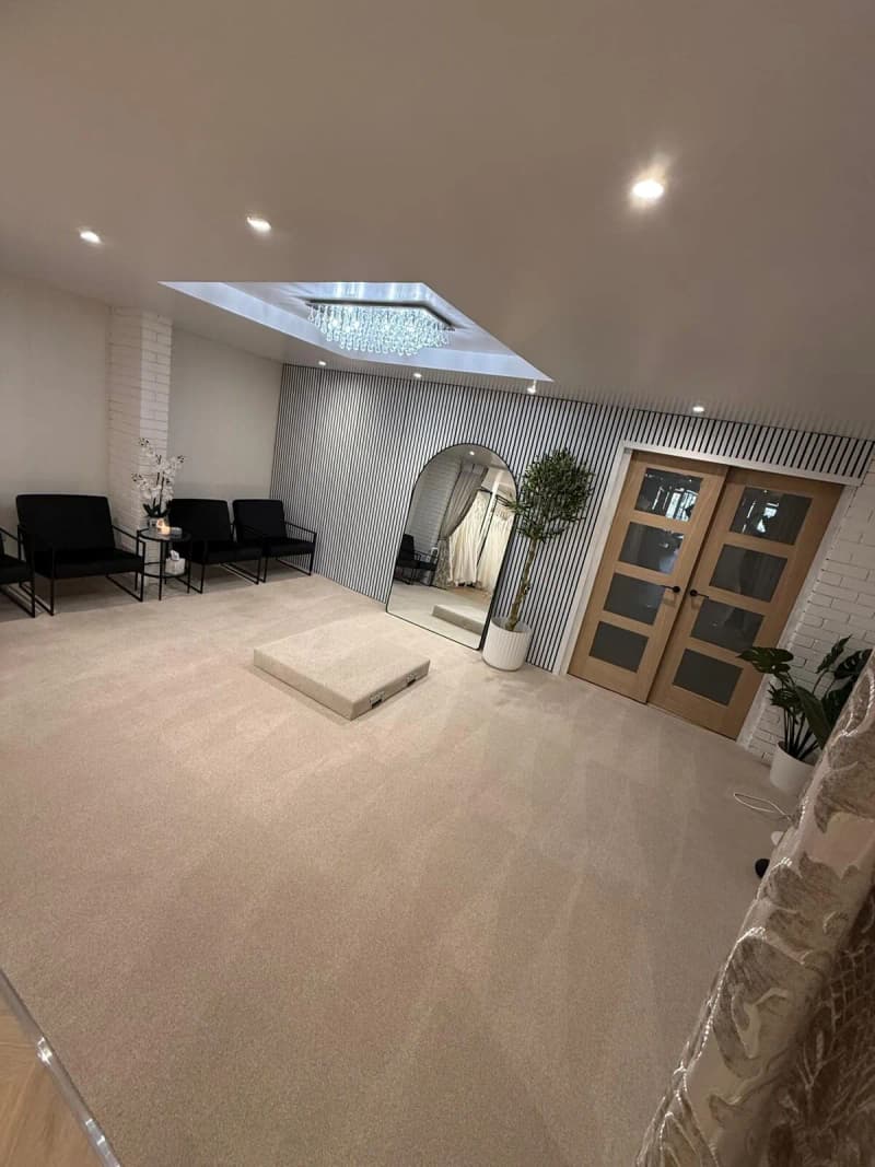The private fitting suite at Bridal by Brittany Ann with a skylight, chandelier and arched mirror